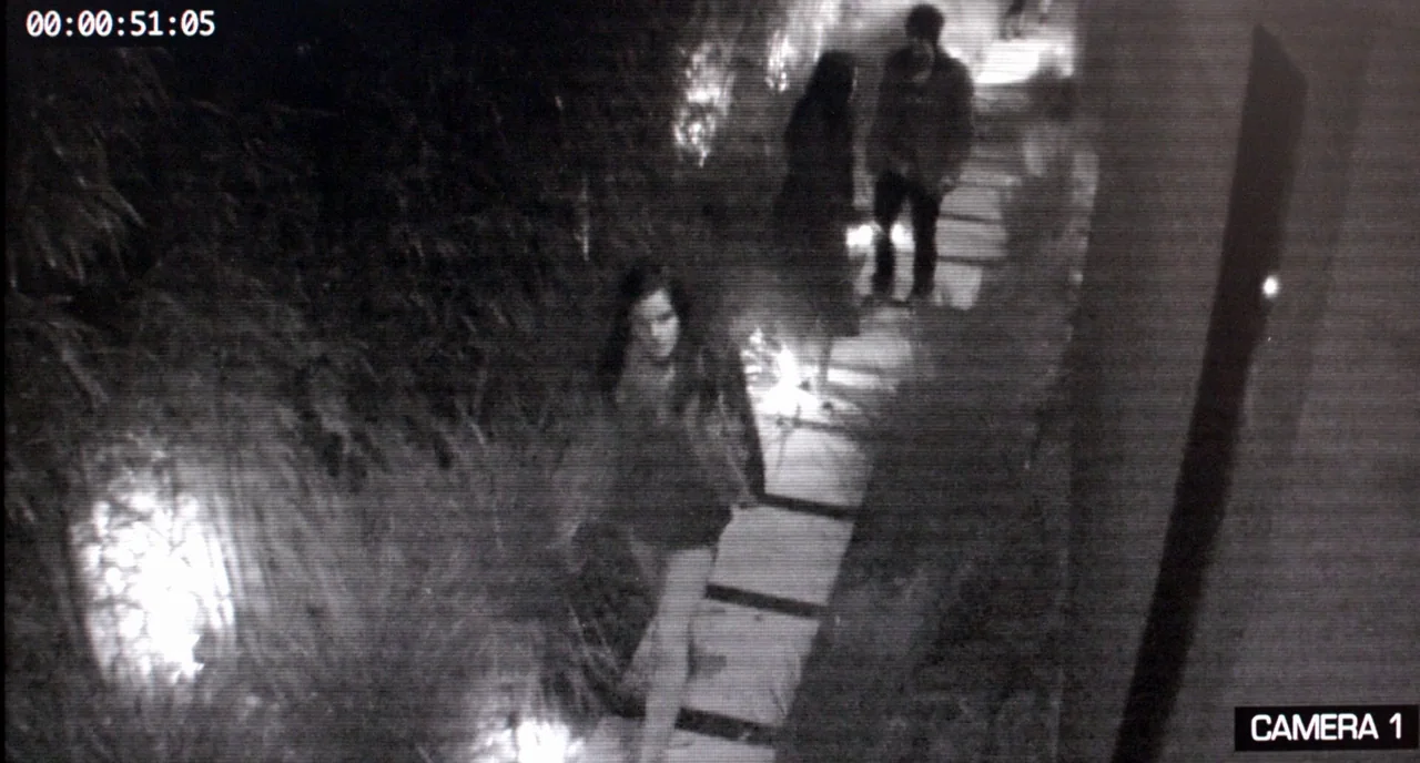 The Bling Ring (2013) movie still: wide — A stone walkway at night is lit by small lamps set into the ground. Three people walk in a line along the…