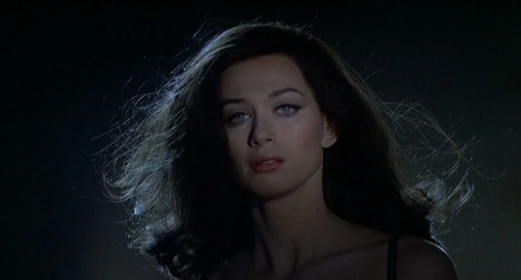 Blood From The Mummy’s Tomb (1971) movie still: closeup — A dark outdoor environment with a woman centered in the frame. The woman stands against a…