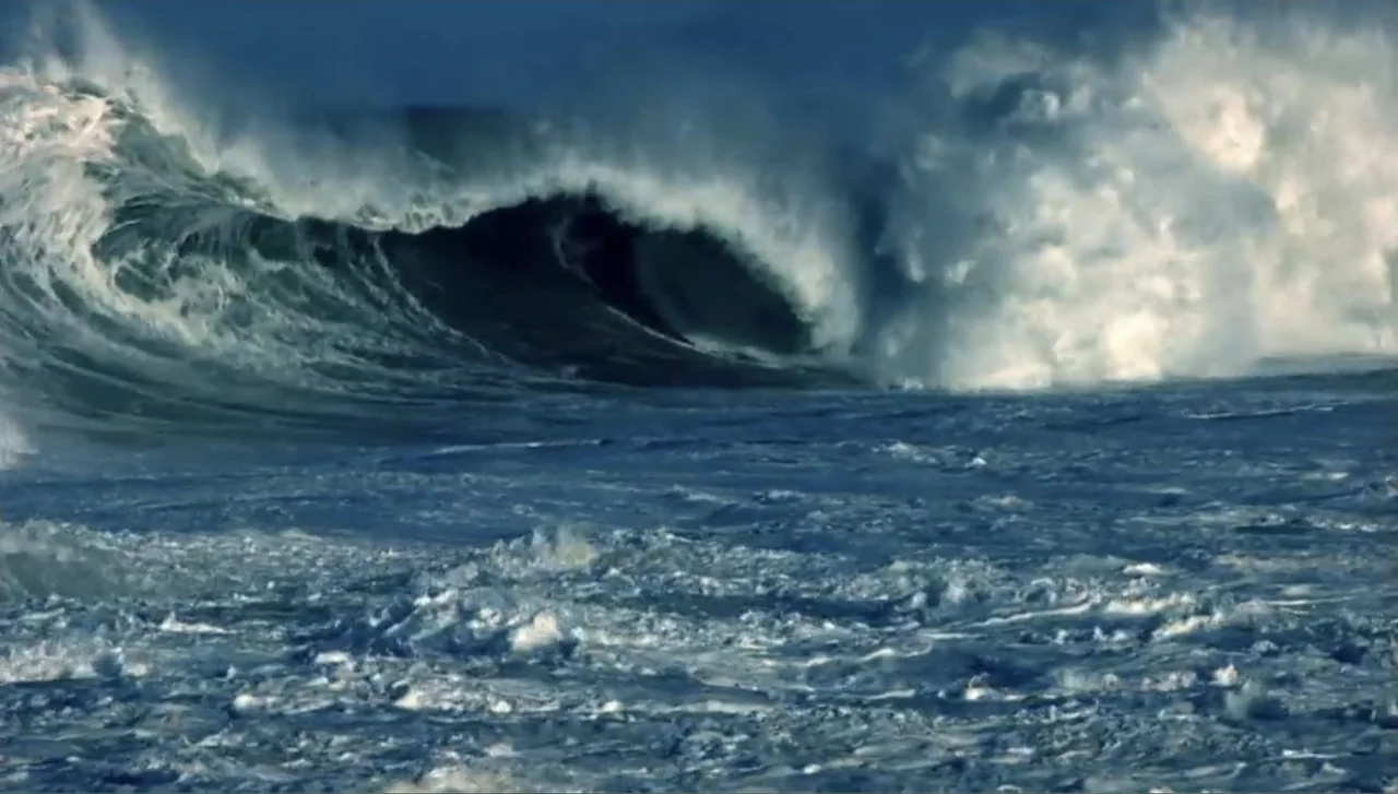 Islands of Creation (2015) movie still: wide — A vast expanse of turbulent ocean water features a large, breaking cresting wave. White sea foam…