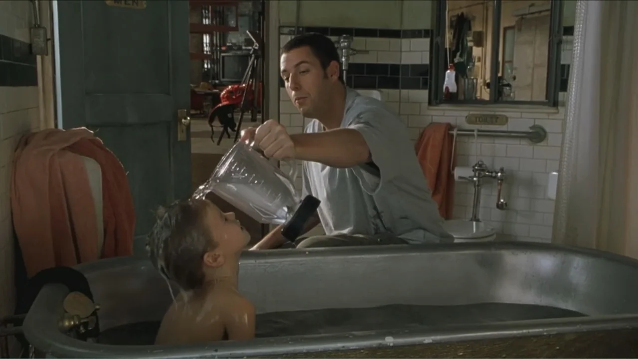 Big Daddy (1999) movie still: medium — A tiled bathroom features a metal bathtub against a wall with dark trim. A man sits beside the tub pouring…