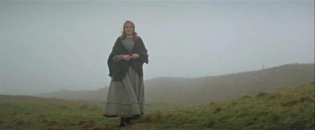 Far from the Madding Crowd (1967) movie still: fullbody — A woman stands in a vast expanse of rolling grassy hills covered in thick fog. The figure…