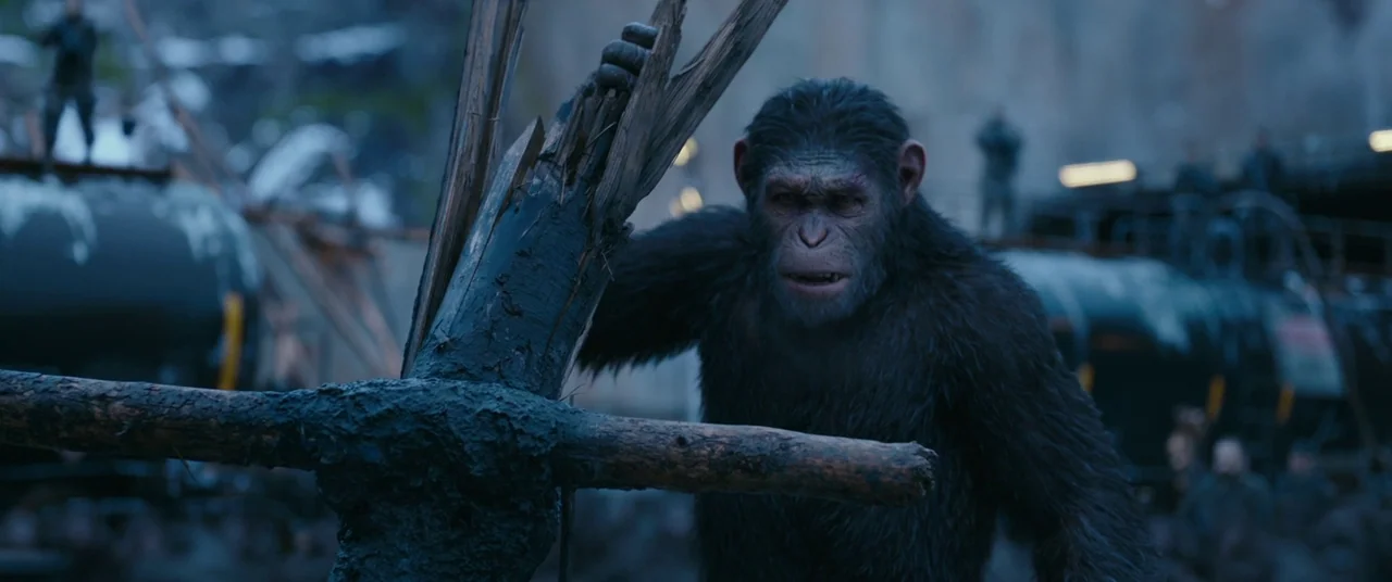War for the Planet of the Apes (2017) movie still: medium — A cluttered outdoor industrial train yard features oil tankers and scattered wooden…