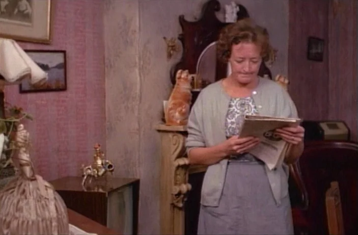 Quackser Fortune Has a Cousin in the Bronx (1970) movie still: medium — A dated 1950s living room features pink wallpaper and a wooden fireplace…