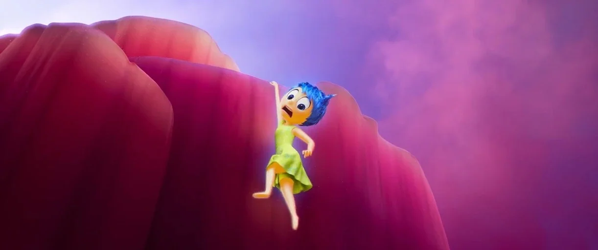Inside Out 2 (2024) movie still: wide — A cartoon character clings to the edge of a massive, smooth magenta rock formation. The background consists…