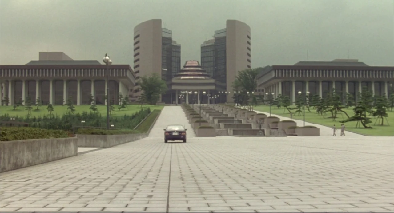 Godzilla vs. SpaceGodzilla (1994) movie still: establishing — A sprawling government complex features modern brutalist buildings and a central…