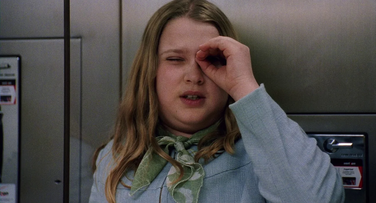 The Weather Man (2005) movie still: medium — A young person stands inside a metallic elevator with brushed steel walls. She forms a circle with her…