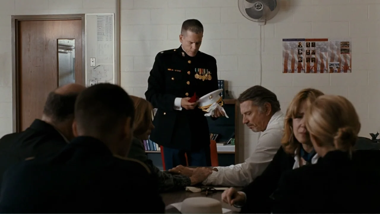 Taking Chances (2011) movie still: medium — A utilitarian office space with white concrete block walls and a wall-mounted fan. A marine officer…