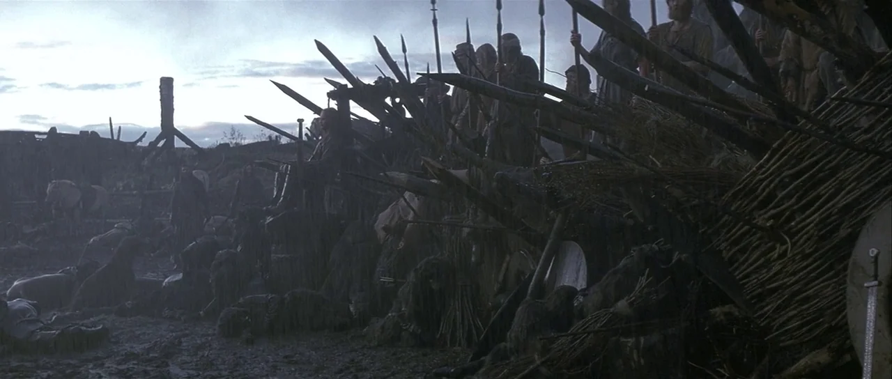 The 13th Warrior (1999) movie still: wide — A rain-soaked battlefield features a defensive barrier constructed from sharpened wooden stakes and…