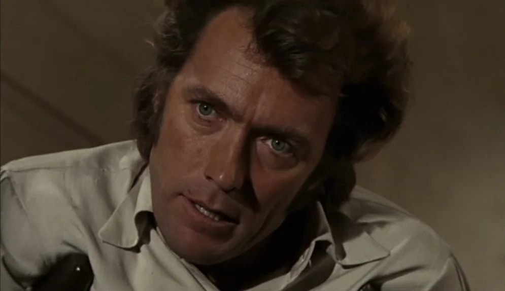 The Beguiled (1971) movie still: closeup — A dimly lit room with muted neutral wall colors serves as the background. A man looks toward the left of…