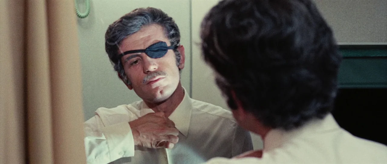 Death Walks On High Heels (1971) movie still: closeup — A man adjusts his shirt collar while looking into a mirror in a bathroom. The reflection…