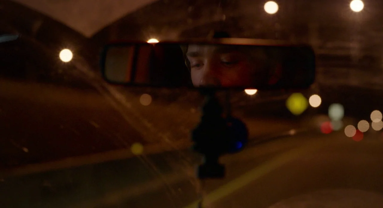 Lean on Pete (2017) movie still: closeup — The interior of a moving vehicle is dark with blurred lights outside. A young man's eyes are visible in…