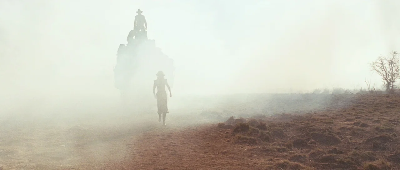 Australia (2008) movie still: wide — A woman runs through a hazy, dusty field toward a rider on a horse. The thick fog obscures the background and…