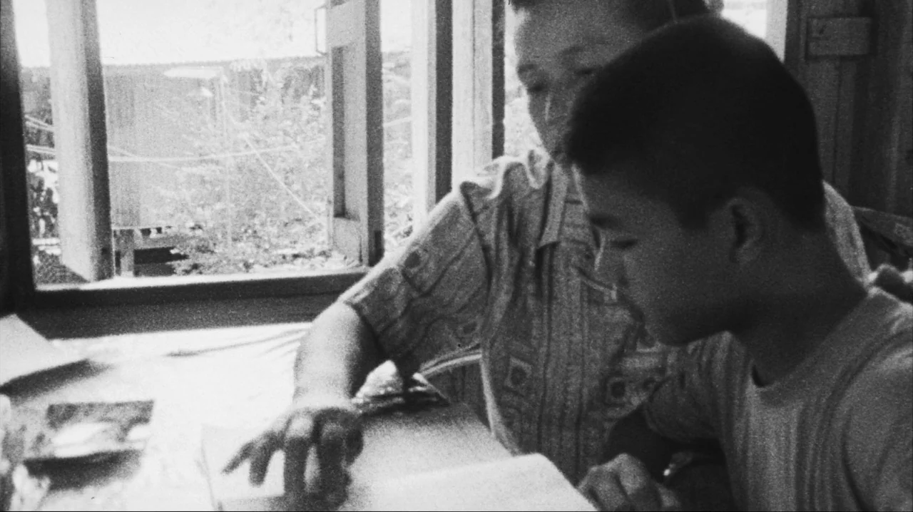 Mysterious Object at Noon (2000) movie still: medium — A bright room with a large window looking out onto blurry greenery. An adult woman and a…