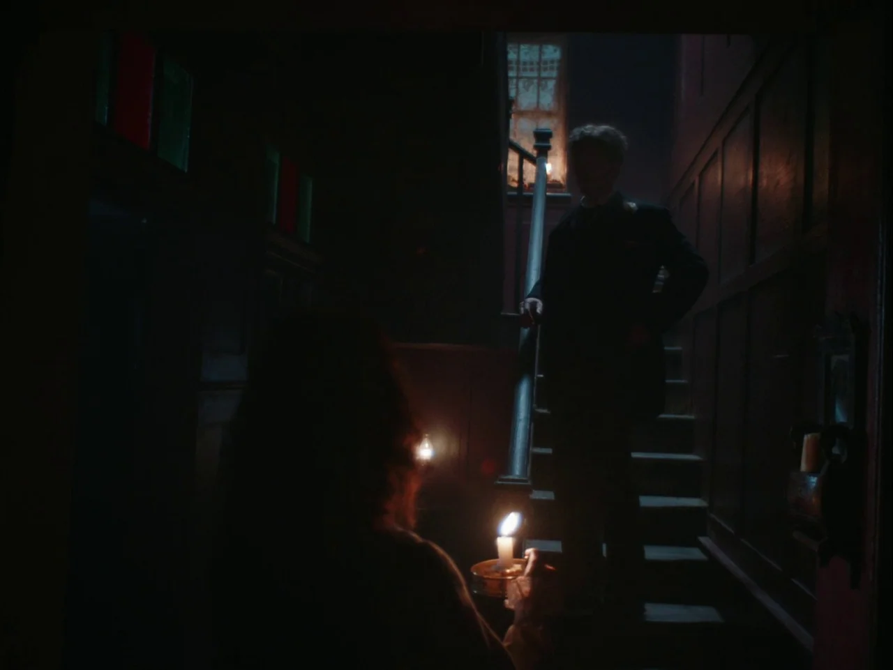 The Electrical Life of Louis Wain (2021) movie still: medium — A dark wooden staircase at night features panelled walls and a dim window above. One…