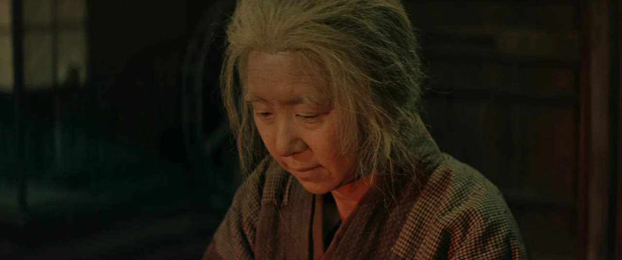 Ballad Of Narayama (1958) movie still: medium — A dimly lit, rustic interior features dark wood walls and shadowed corners. An elderly woman in a…