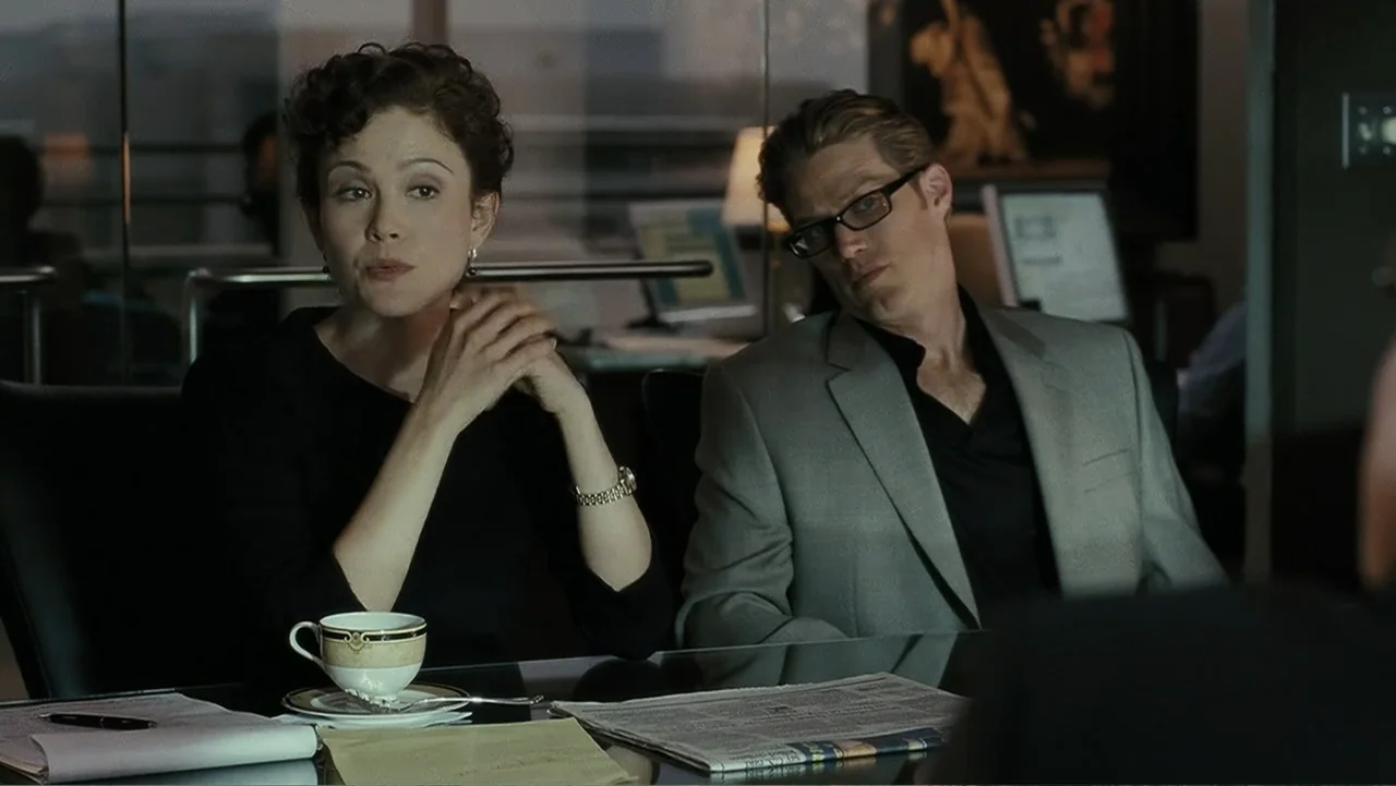 Mr. Brooks (2007) movie still: medium — A professional corporate setting featuring a glass-topped table with papers and a teacup. A woman and a man…