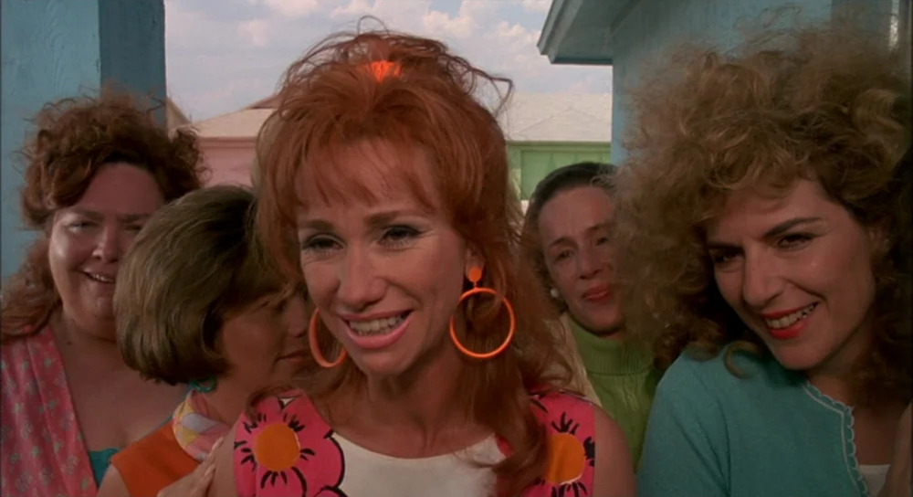 Edward Scissorhands (1990) movie still: medium — A group of women stand outdoors in front of colorful pastel suburban houses. The subjects are…
