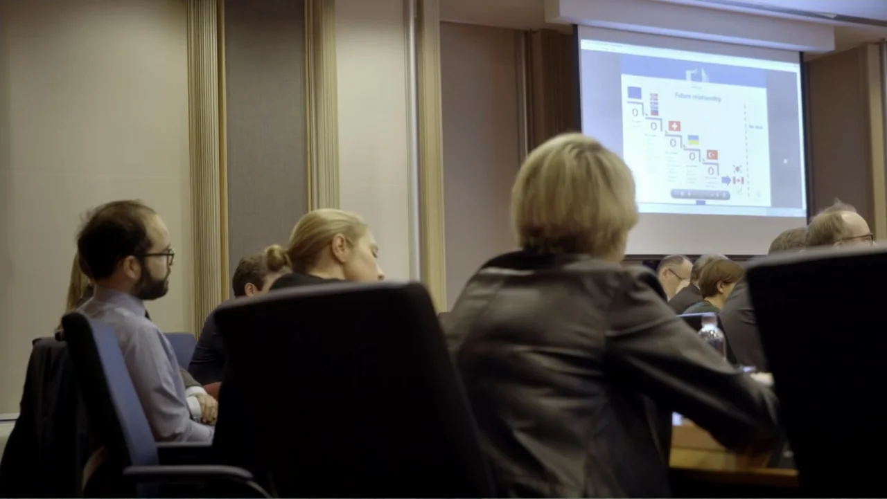 Brexit: Behind Closed Doors (2019) movie still: medium — A modern professional conference room with vertical wall paneling and a large projection…