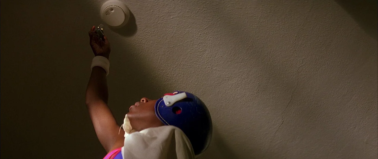 George Washington (2000) movie still: medium — A textured off-white ceiling serves as the backdrop for a close interaction. A child wearing a sports…