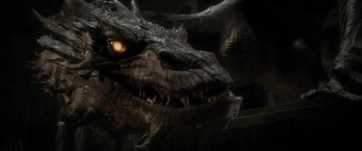 The Hobbit: The Desolation of Smaug (2013) movie still: closeup — A gargantuan dragon lies within a dimly lit stone chamber with textured, craggy…