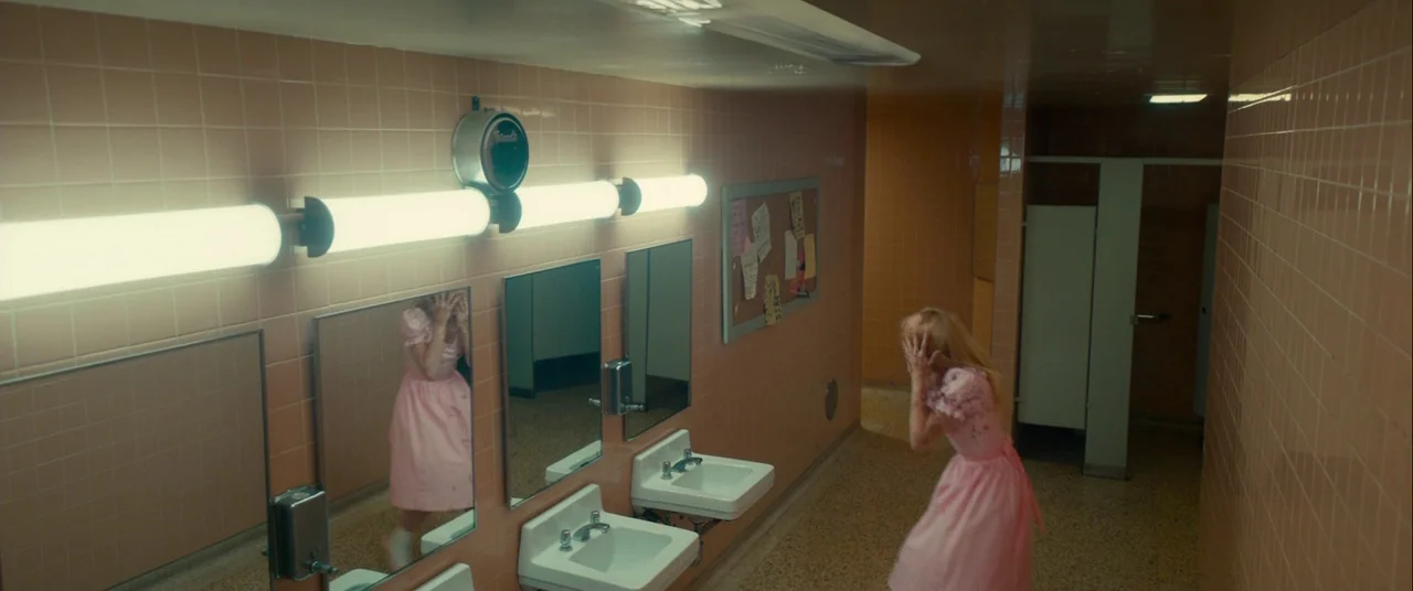 Scary Stories to Tell in the Dark (2019) movie still: wide — A public restroom features floor-to-ceiling peach ceramic tiles and multiple…