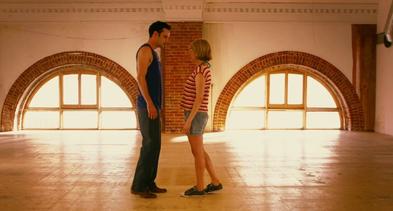 Take This Waltz (2011) movie still: fullbody — A spacious, brightly lit loft features exposed brick pillars and large arched window structures. Two…