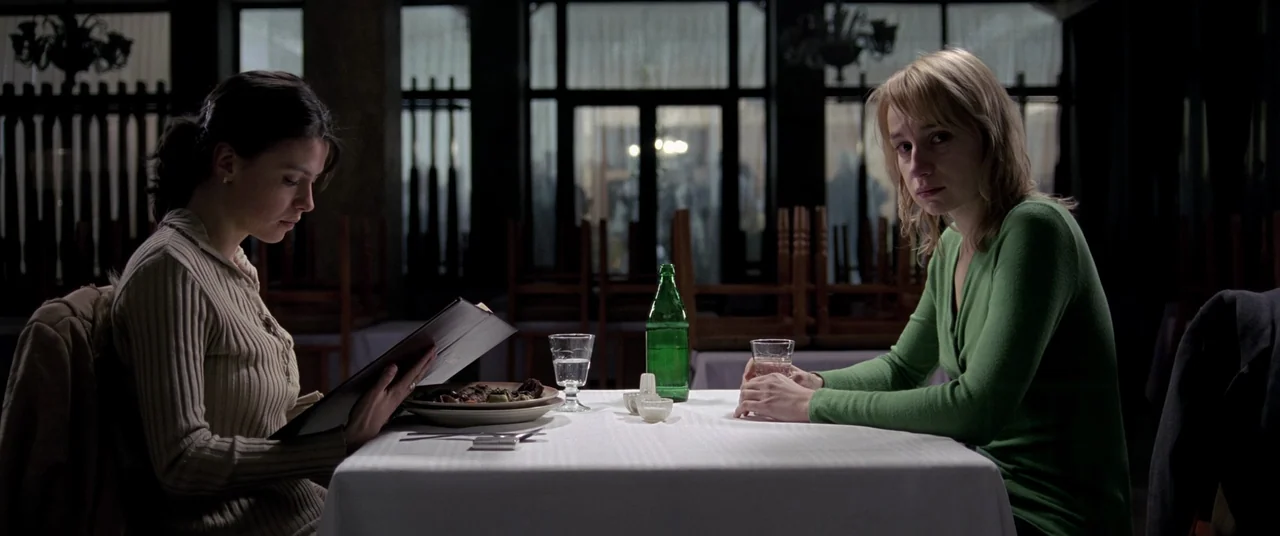 4 months, 3 Weeks and 2 Days (2007) movie still: medium — A dimly lit restaurant interior with stacked chairs and dark windows in the background.…