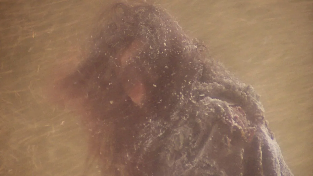 The Bride with White Hair II (1993) movie still: closeup — A person moves through a thick, golden-brown dust storm obscuring the surrounding desert…
