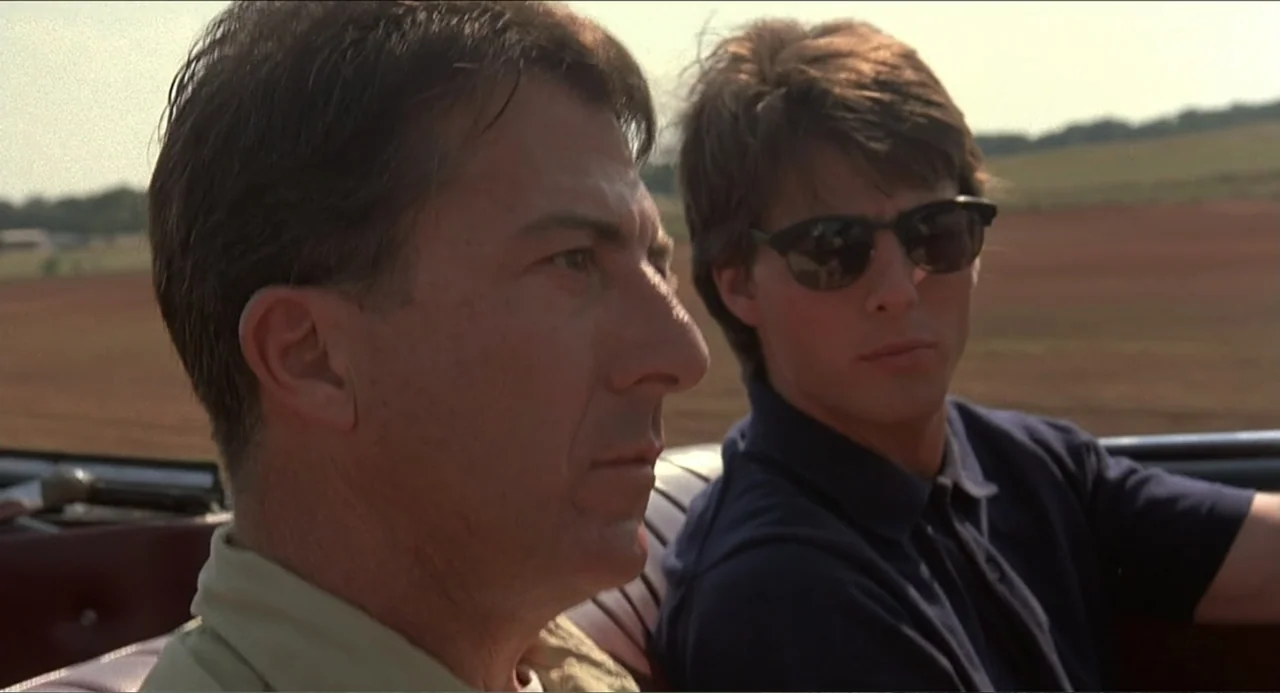 Rain Man (1988) movie still: medium — Two men sit in a convertible car traveling through an open flat landscape. The man on the left drives while…