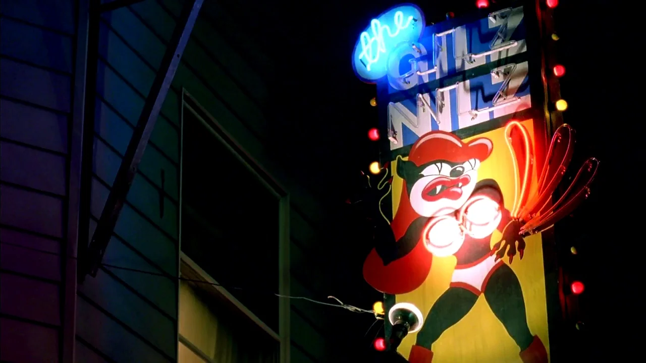 Belly (1998) movie still: wide — A vertical exterior neon sign depicts a cartoon character against a dark building facade. The sign features glowing…