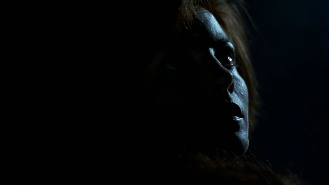 Jason Goes To Hell (1993) movie still: closeup — A dark, unidentifiable space where a single light catches the side of a face. The subject turns…