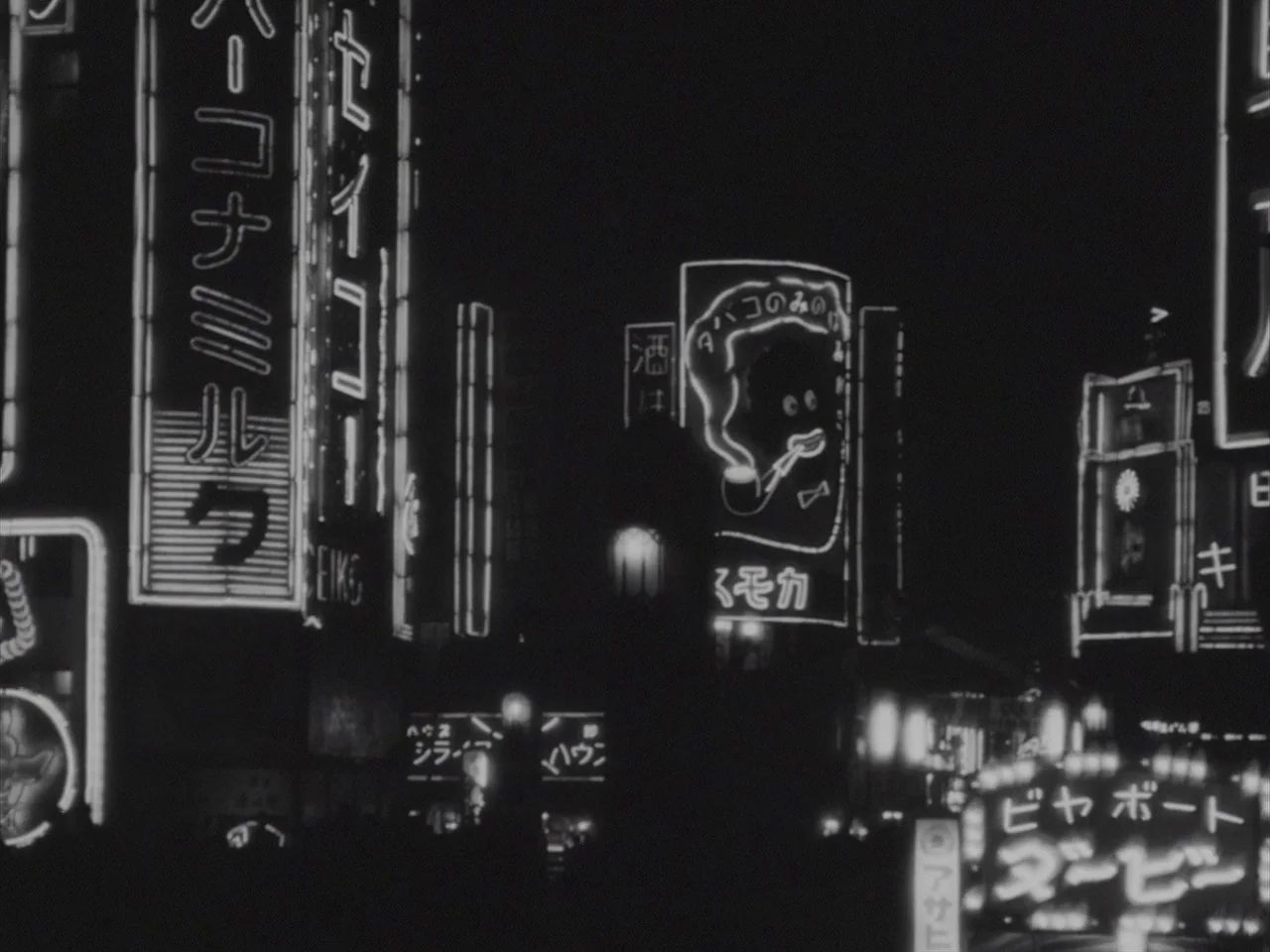 Godzilla Raids Again (1955) movie still: establishing — A dense urban intersection at night featuring glowing Japanese neon advertisements on tall…