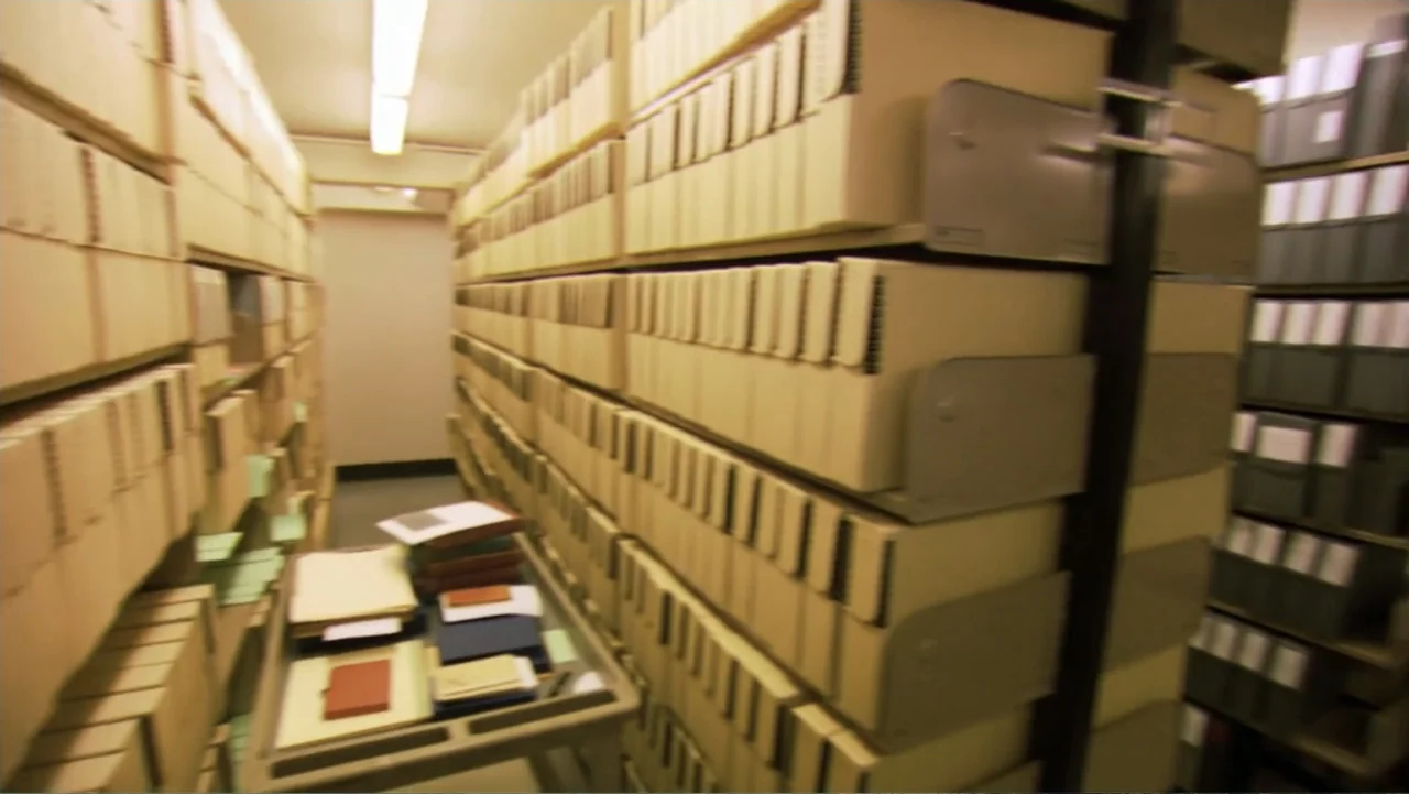 David McCullough: Painting with Words (2008) movie still: wide — An institutional archive room features long metal shelves densely packed with beige…