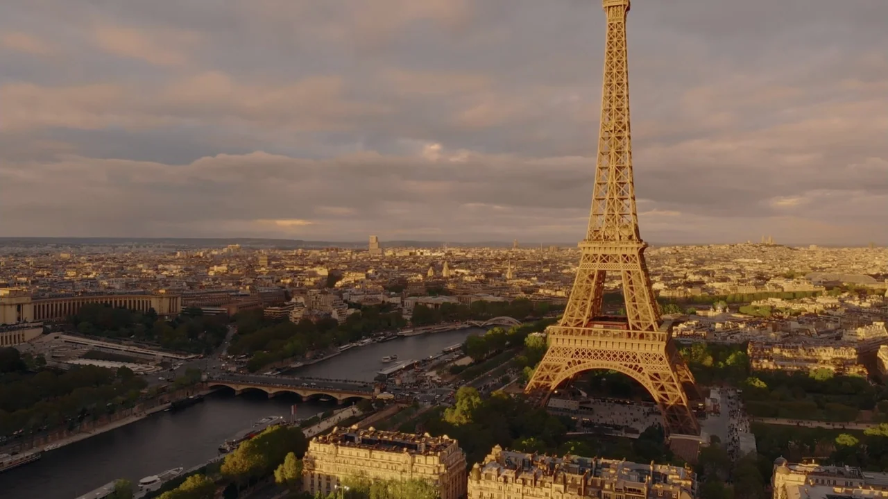 Red, White & Royal Blue (2023) movie still: establishing — An expansive aerial view of Paris at sunset featuring the Eiffel Tower. The Seine river…