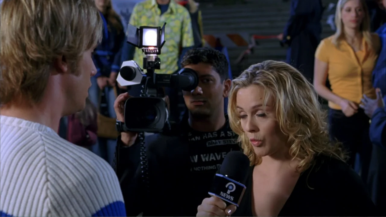 Scooby-Doo 2: Monsters Unleashed (2004) movie still: medium — A nighttime outdoor setting with a news crew filming a man in a sweater. The reporter…