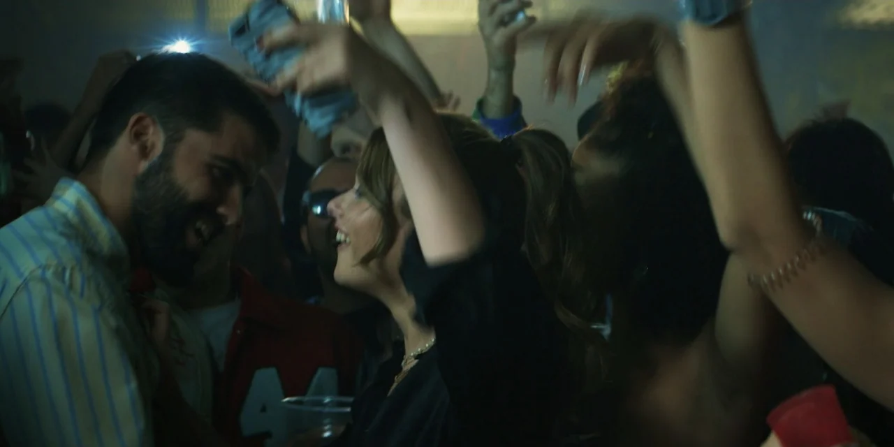 My Fault (2023) movie still: medium — A crowded nightclub dance floor with many people moving in the background. A woman and a man are standing…
