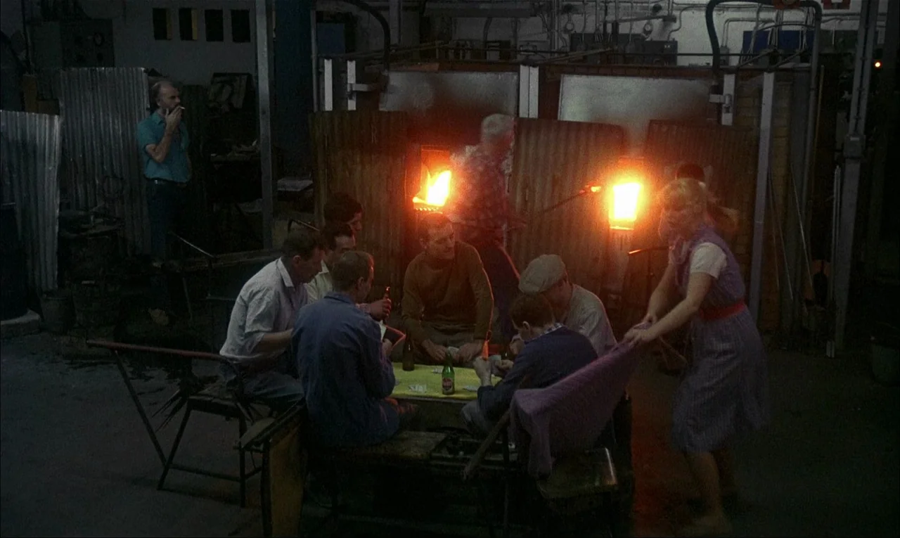 My Life As A Dog (1985) movie still: wide — A dimly lit industrial glass factory with glowing furnaces visible in the center background. A small…