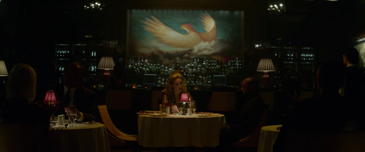 Triple 9 (2016) movie still: wide — A high-end restaurant features round tables with white cloths and a large phoenix mural. People dine in a…
