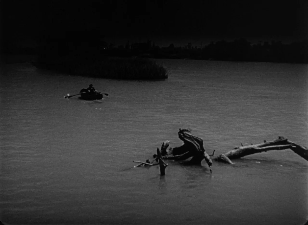 House by the River (1950) movie still: wide — A dark river scene with a large piece of driftwood in the foreground. A small rowboat with a single…