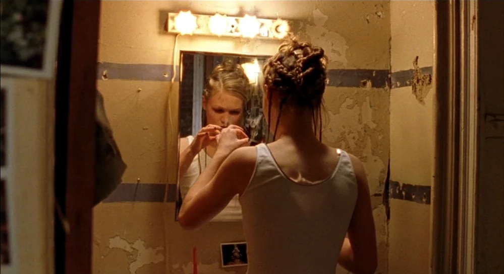 Hamlet (2000) movie still: medium — A small bathroom features peeling beige paint with a horizontal blue stripe and vanity lights. A young woman…