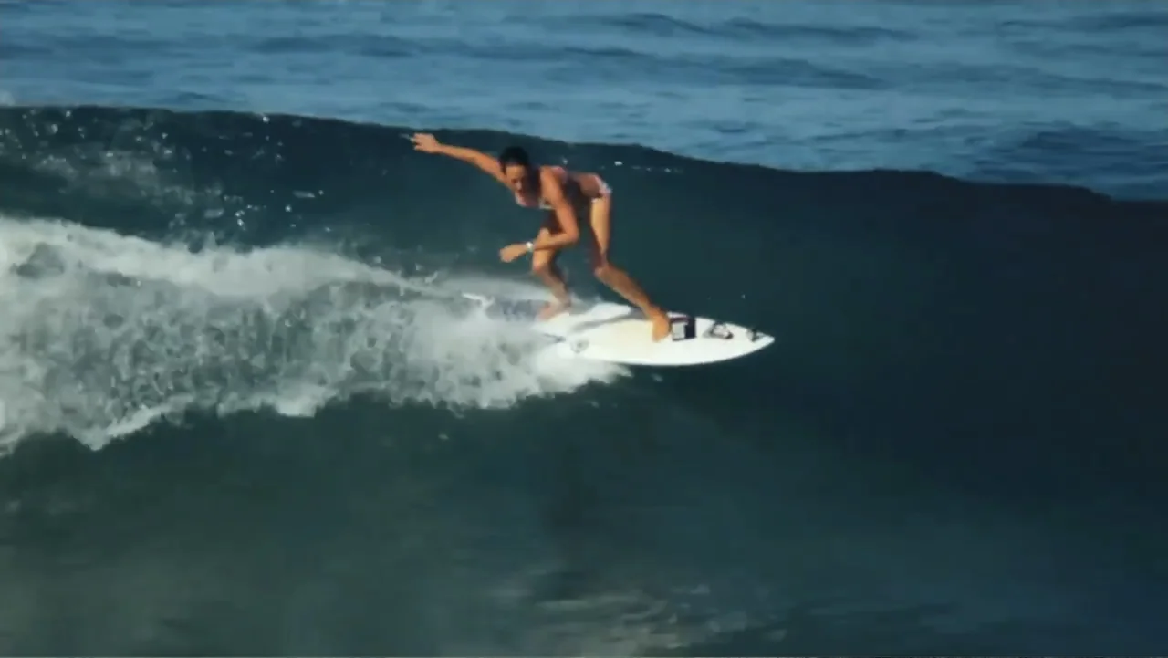 El sueño (2020) movie still: fullbody — A surfer rides a large breaking ocean wave during a clear day. The surfer maintains balance while navigating…