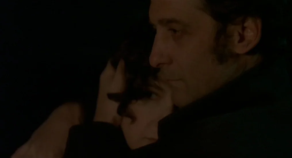 Vendredi Soir (2002) movie still: closeup — Two individuals are visible in an extremely dark setting with minimal environmental detail. A man holds…