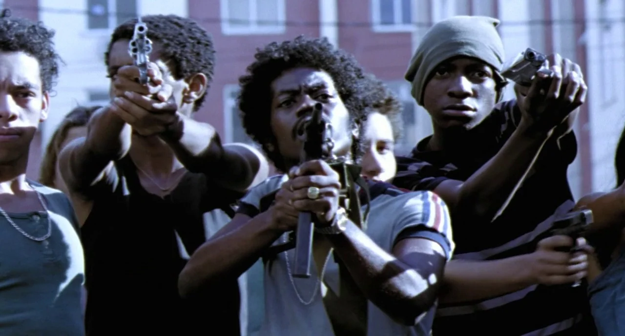 City of God (2002) movie still: medium — A group of young men stands outdoors with urban apartment buildings visible in the background. They are…