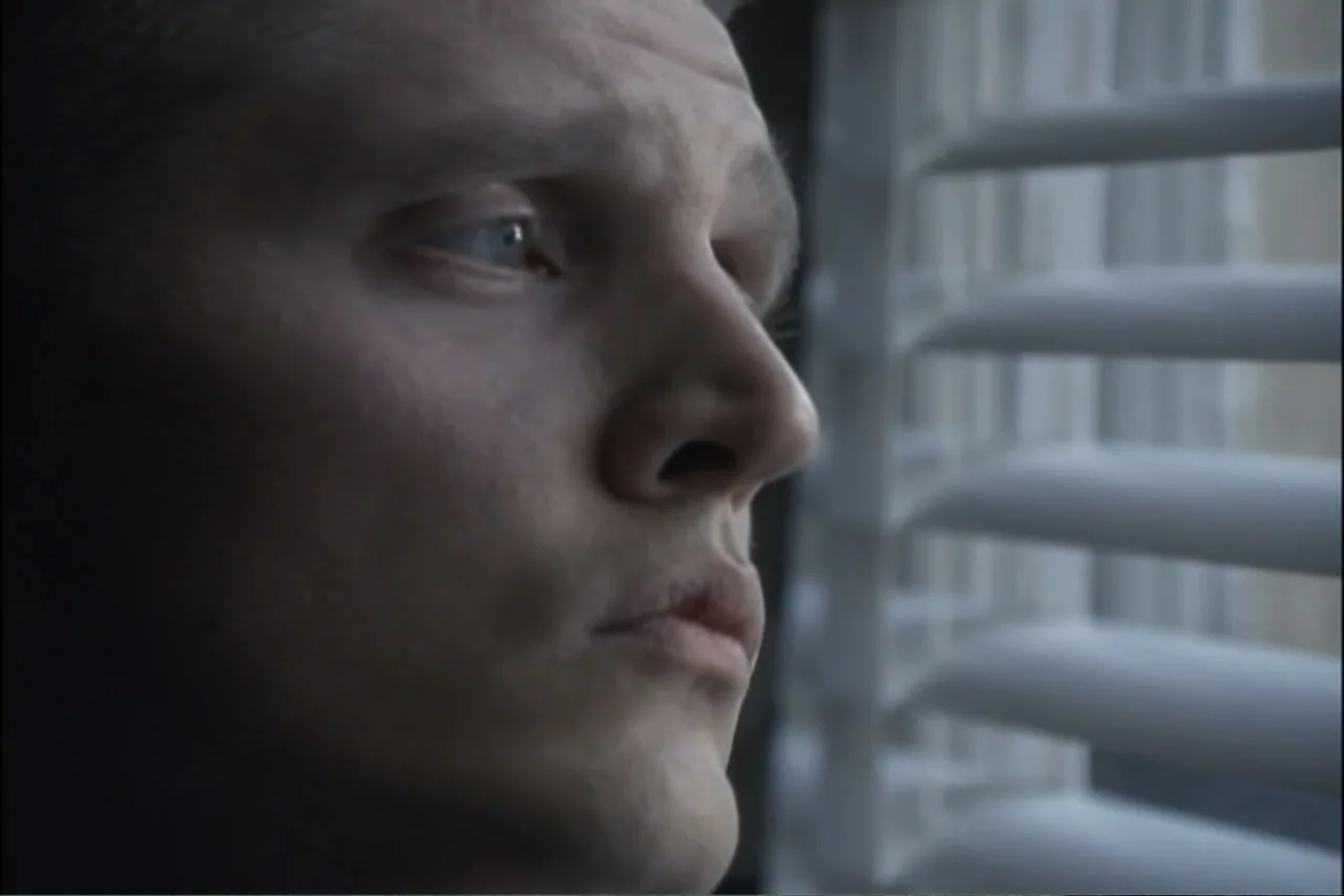 Unification of Japan 61 (2024) movie still: closeup — A close up of a man looking through white horizontal window blinds. The man face is turned in…