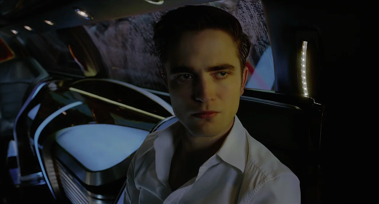 Cosmopolis (2012) movie still: medium — A dark limousine interior features smooth black surfaces and integrated LED light strips. A man sits in the…