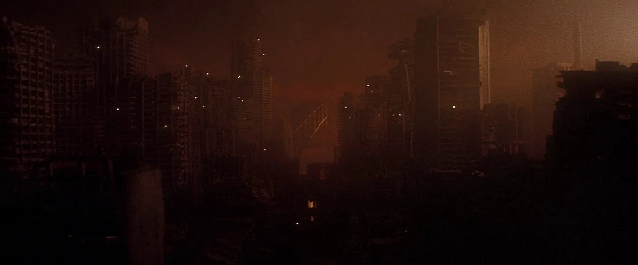 Mad Max Beyond Thunderdome (1985) movie still: establishing — A decimated urban landscape filled with skeletal remains of skyscrapers and heavy dark…