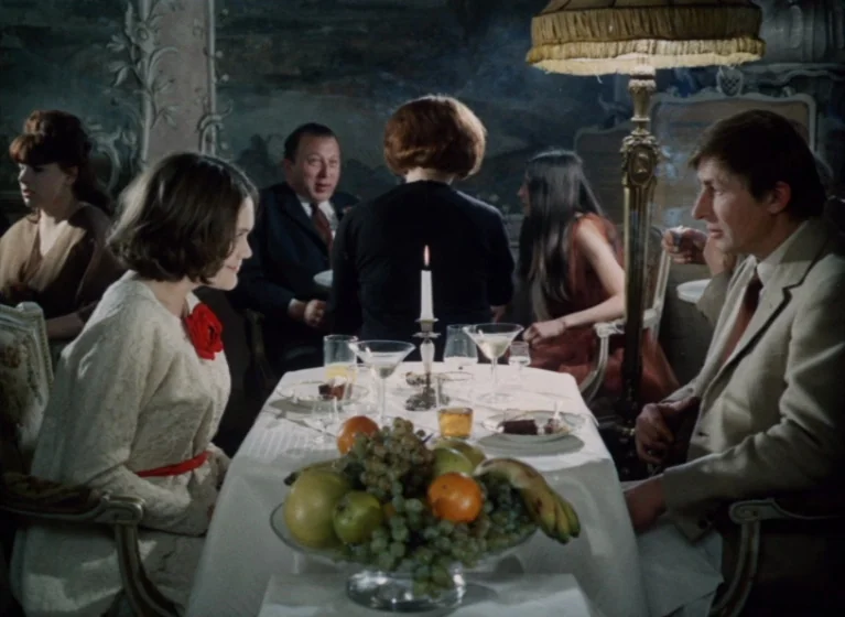 Fruit of Paradise (1970) movie still: medium — An elegant room with ornate wall paneling serves as the backdrop for a dinner. A man and a woman sit…