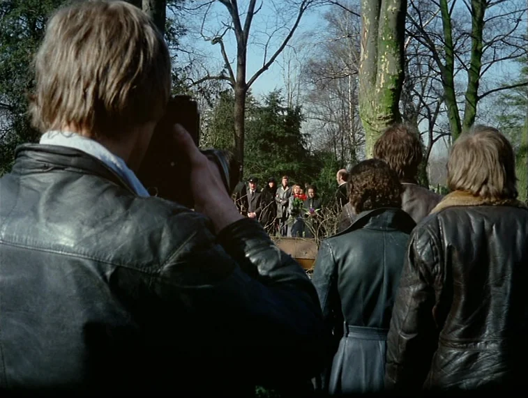 Mother Kusters Goes To Heaven (1975) movie still: medium — A group of people stands in a cemetery surrounded by leafless trees under bright…