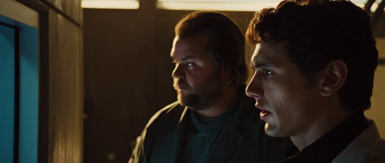 Rise of the Planet of the Apes (2011) movie still: medium — A dimly lit industrial laboratory contains two men watching a illuminated monitor. The…