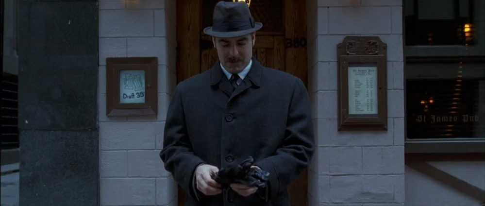 Confessions of a Dangerous Mind (2002) movie still: medium — A man in a wool coat stands outside the brick entrance of a pub. He looks down at his…
